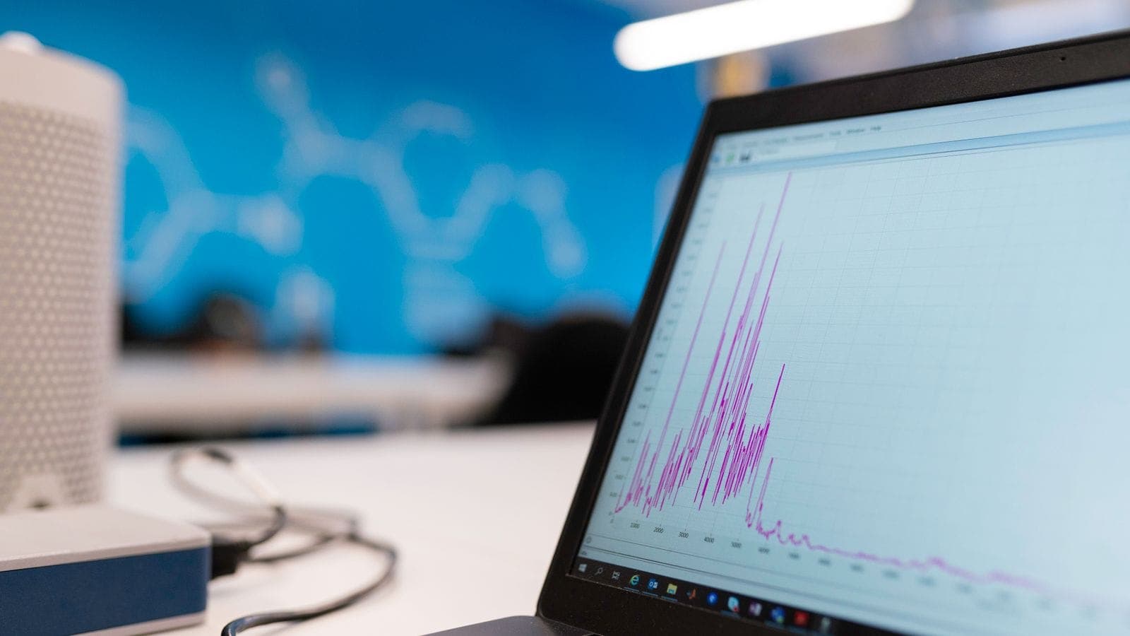 A laptop on a desk displaying a business data analytics line graph in a modern office
