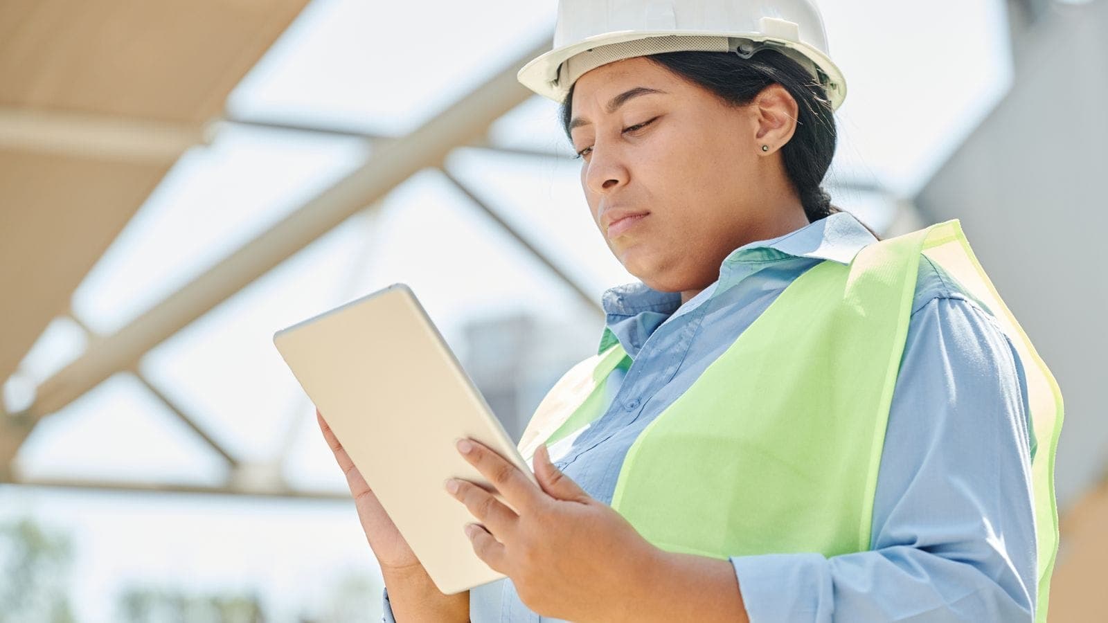 Engineer in a hard hat using a digital tablet at an outdoor construction site