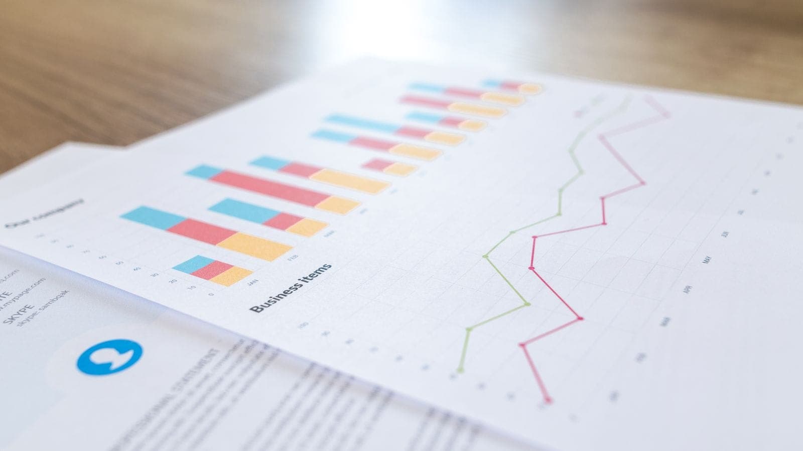 Printed financial report with color bar and line charts on a wooden desk