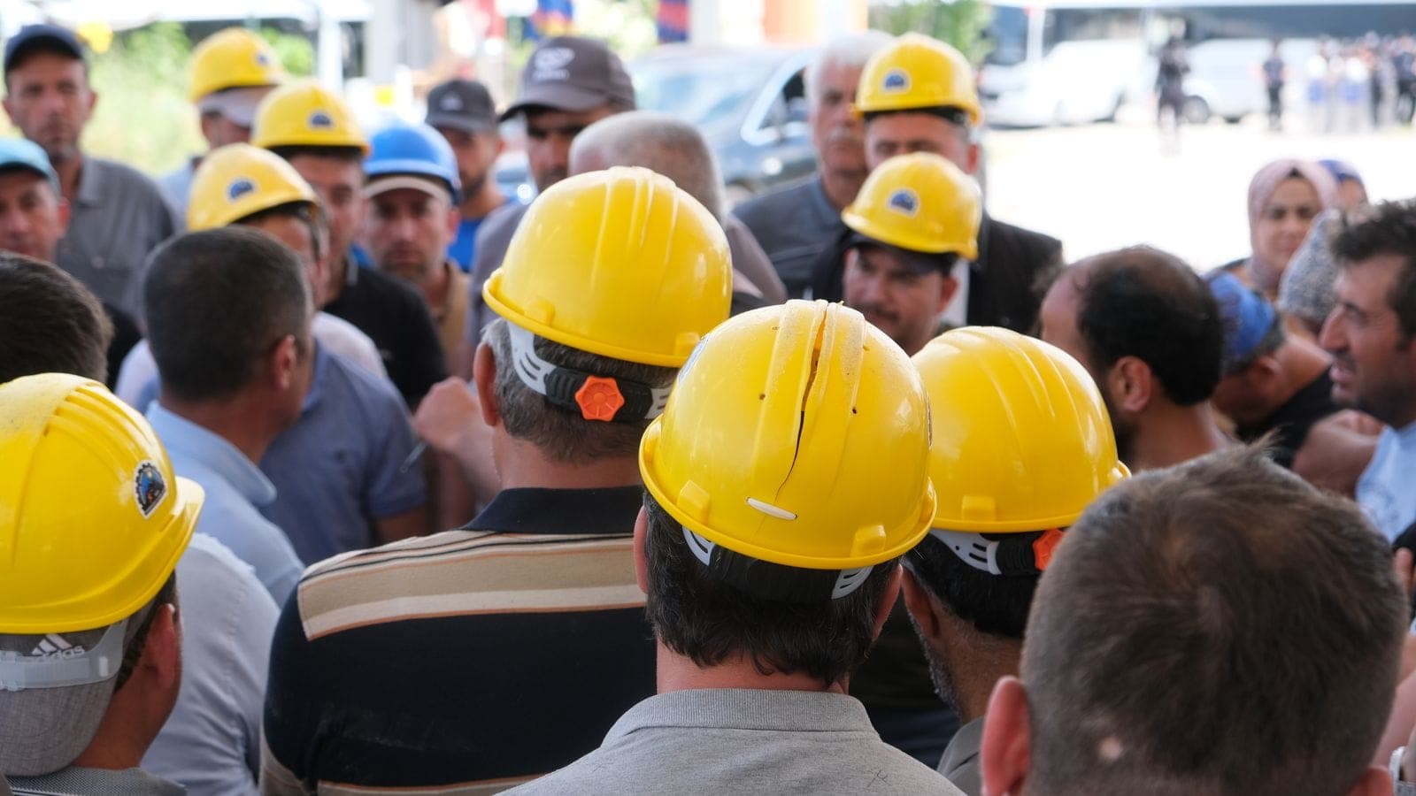 Group of construction workers in yellow hard hats gathered for a briefing at a job site