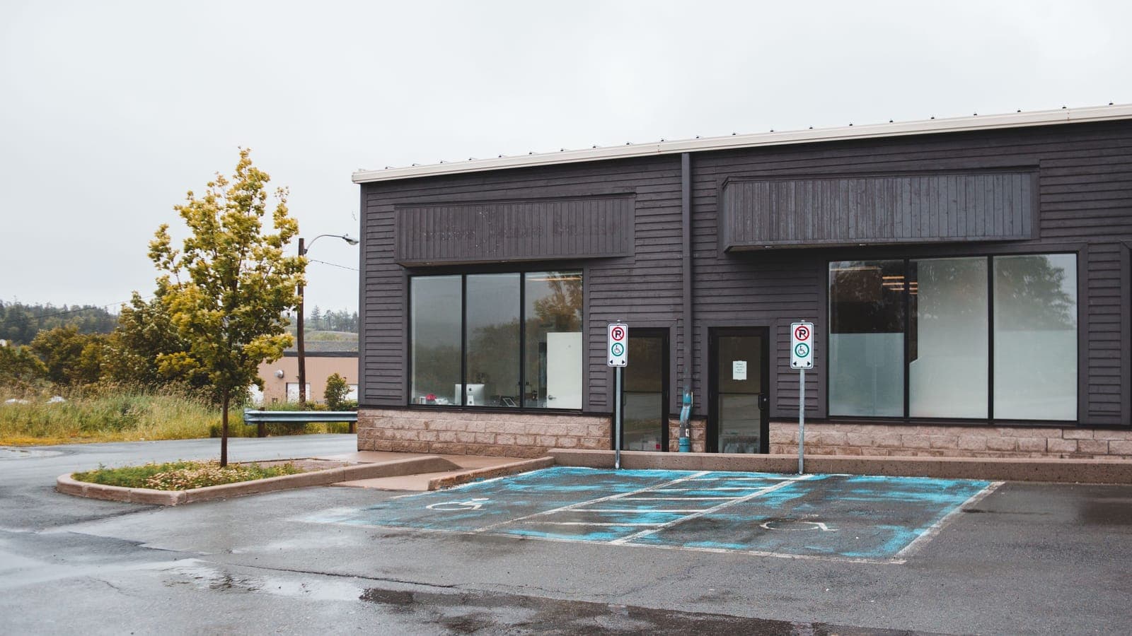 A newly built freestanding retail unit with fresh dark cladding and an empty parking lot, ready to open