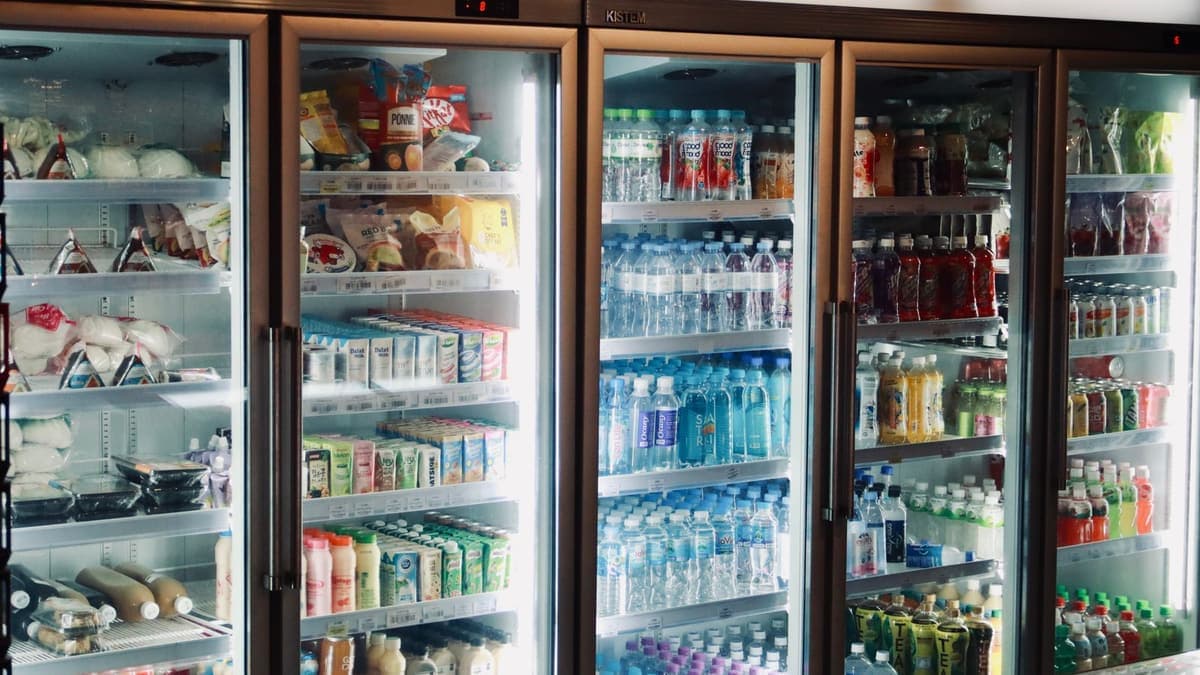 A bank of glass-door refrigerated display cases stocked with beverages in a store