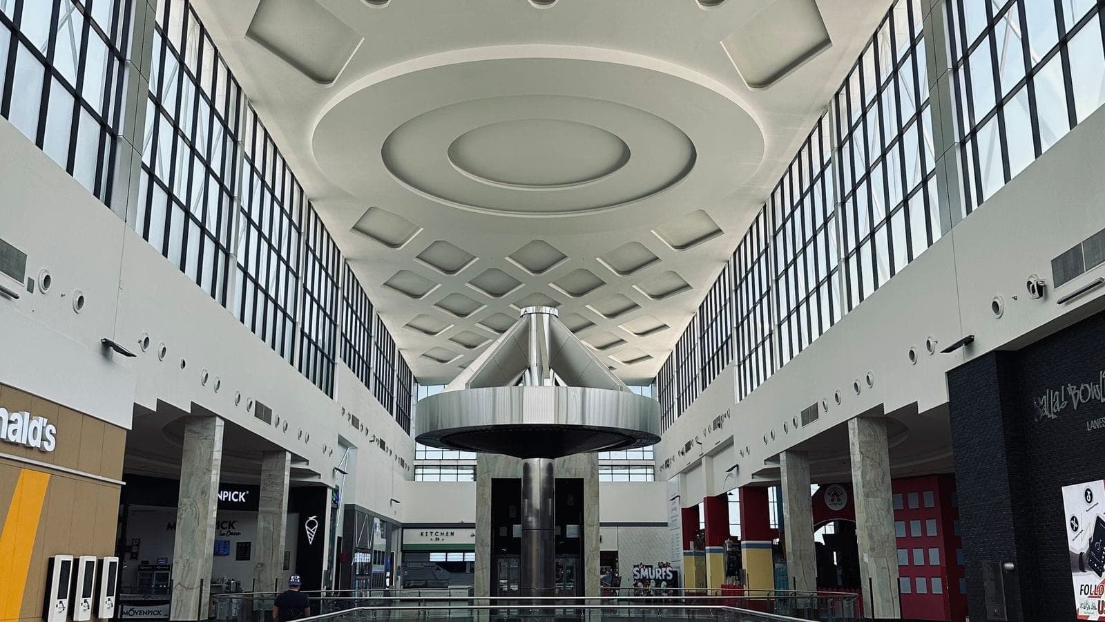 Interior of a modern shopping mall with a geometric ceiling and glass railings