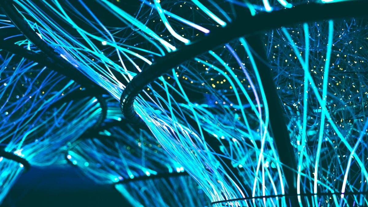 Abstract glowing blue fiber-optic strands against a dark background