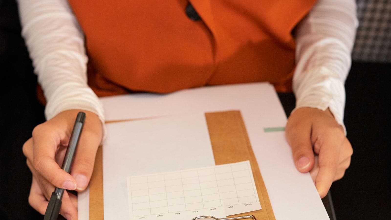 Person holding a clipboard with a planning schedule and pen, organizing project tasks