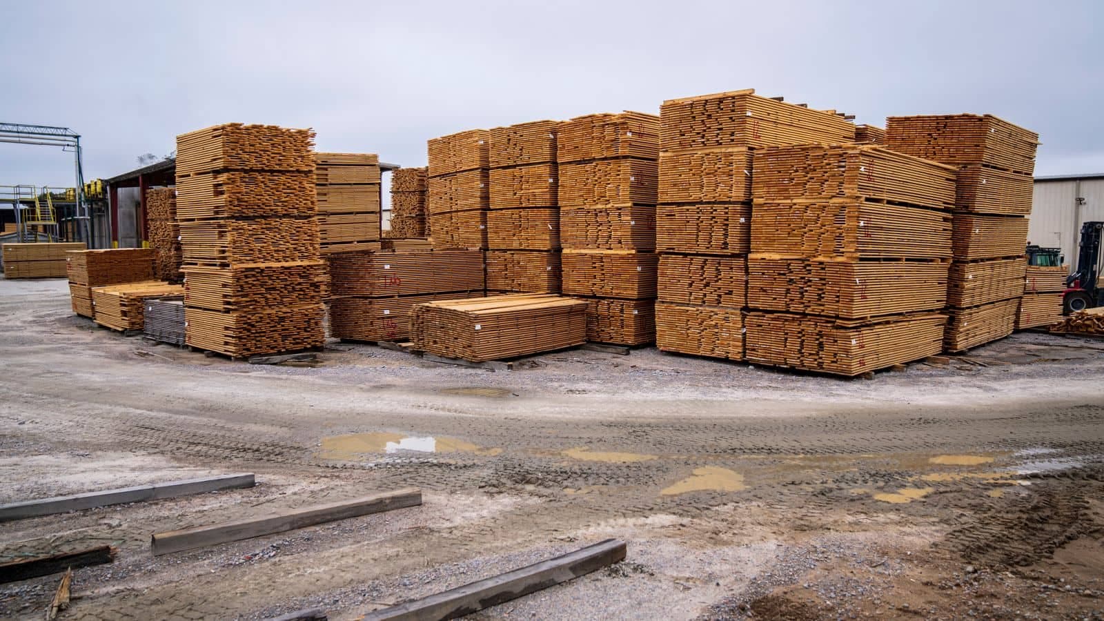 Stacks of wooden planks organized at an outdoor construction supply and lumber yard