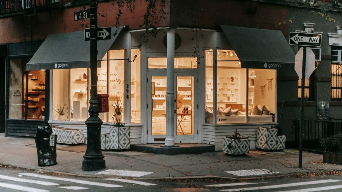 A warmly lit corner retail storefront on a city street at dusk