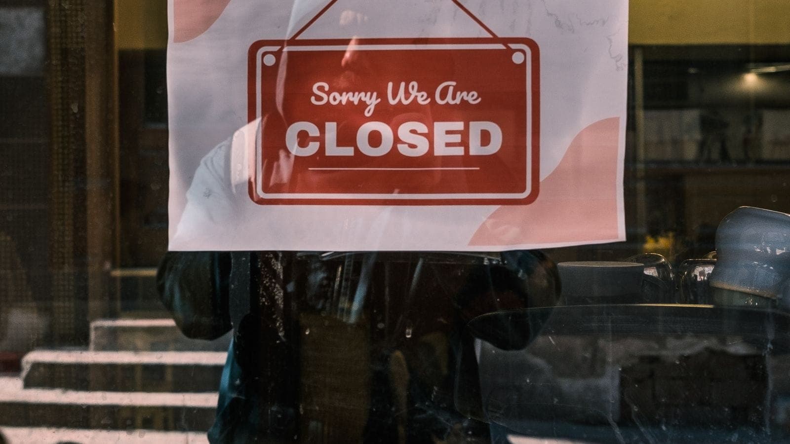 Storefront window displaying a Closed sign, with the street reflected in the glass
