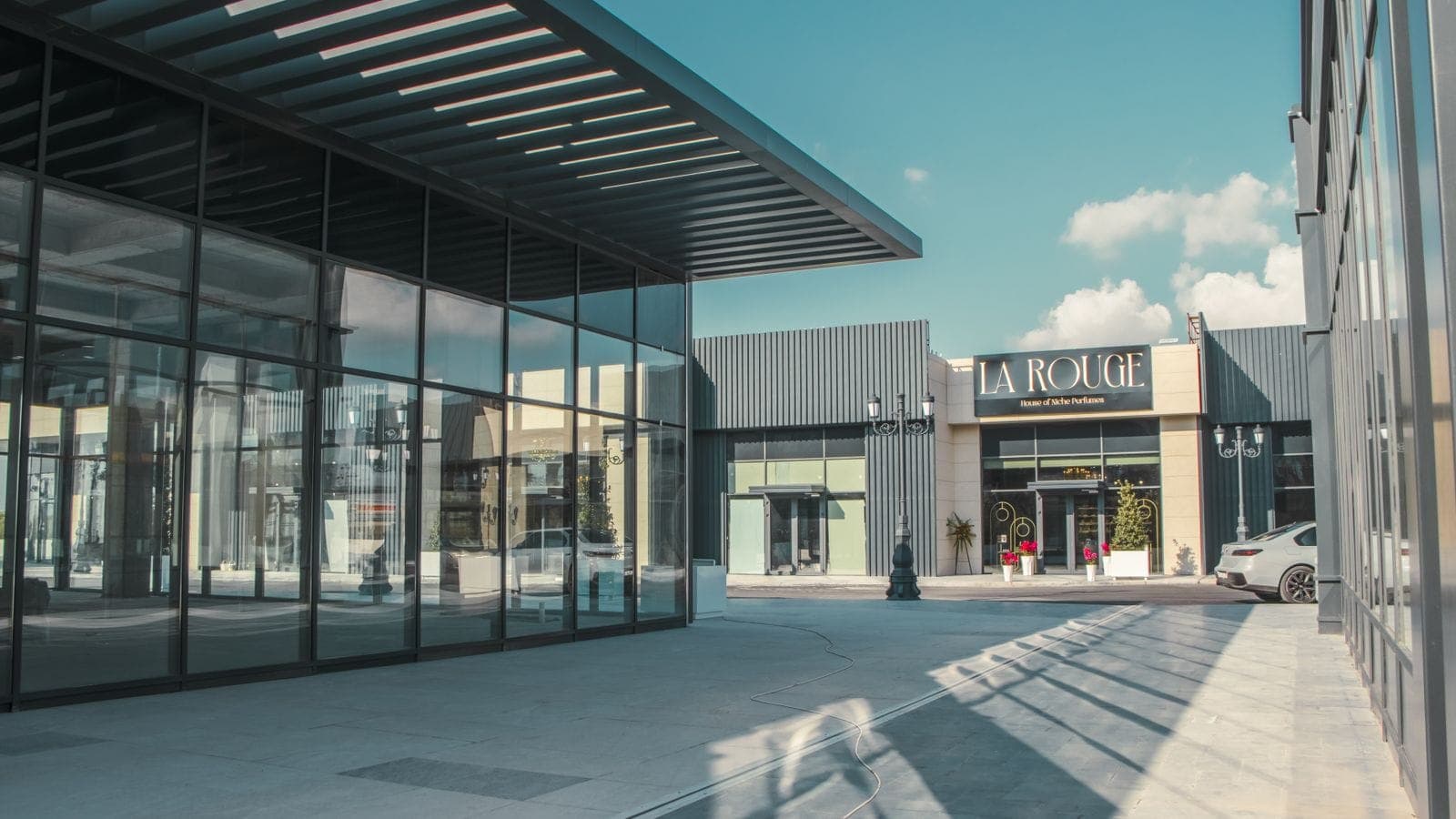 Modern retail plaza with glass storefronts and a clear blue sky