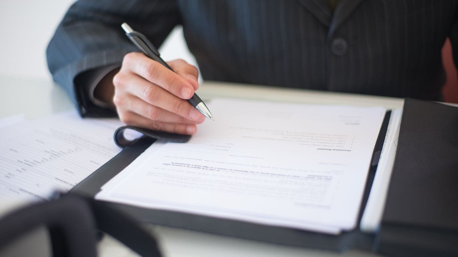 Close-up of a person signing a business contract document with a pen